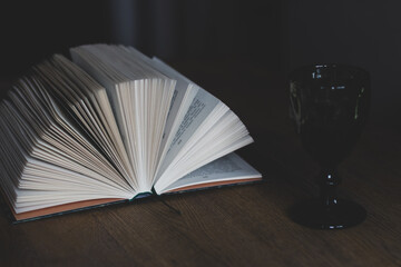 Open book with glass of red wine. Open book with wineglass. Education concept. Reading books. Literature background. Wisdom and knowledge. Book and wine. Cozy home. Evening drinks.