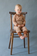 Portrait cute one year old baby girl, sitting on a wooden chair