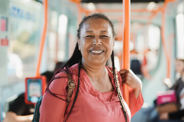 African senior woman smiling on camera inside tram - obrazy, fototapety, plakaty