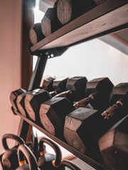 Mancuernas sobre un rack junto a kettlebells