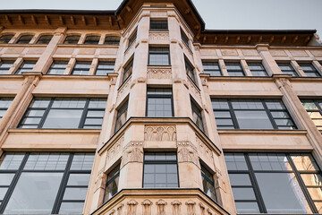 A stone building with large windows and a ledge. View from below of Wroclaw, Poland. Close-up.
