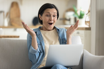 Happy excited mature customer woman getting good news, feeling overjoyed, cheerful, looking at...