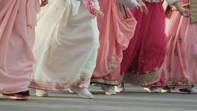 Unrecognizable Hare Krishna women dancing in traditional dresses on the street