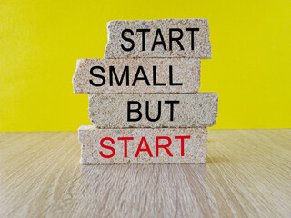 Start small but start symbol. Concept words 'Start small but start' on brick blocks on a beautiful yellow background. Business, motivational concept.