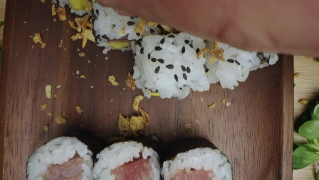 Slow-motion shot of lot of sushi bite size pieces decorated with greens served on tray ready to be eaten. Close-up