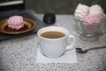 cup of coffee and bowl of sweet marshmallows on the table