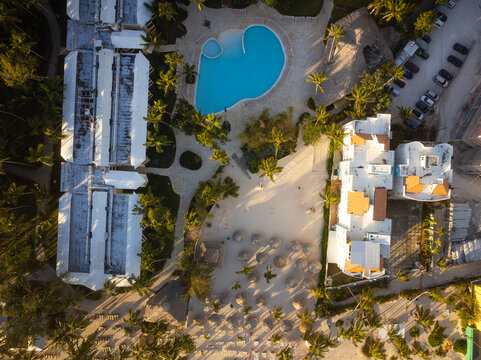 Shooting from a drone. Resort. Hotel rooftops, swimming pool, car parking, tropical plants. Recreation, tourism, infrastructure, climate, buildings, construction.