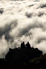 Naklejka na ściany i meble Two people on top of a mountain above the clouds