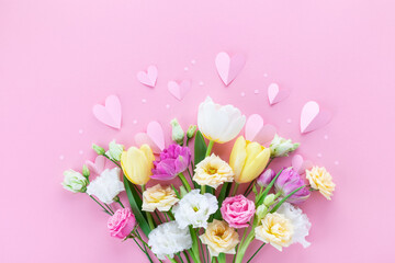 Bouquet of beautiful spring flowers and paper hearts on pastel pink table for Happy mothers day....