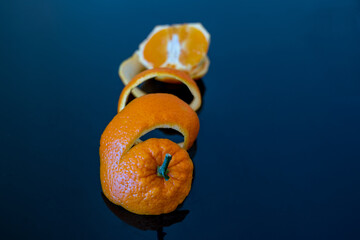 close-up on a spirally cut orange peel and an orange cut in half on a dark blue background