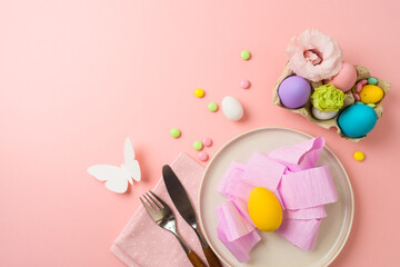 Easter holiday festive table setting with plate, easter eggs and party decorations on pink background. Top view, flat lay