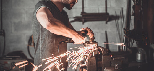 Confident young man grinding with sparks in repair shop