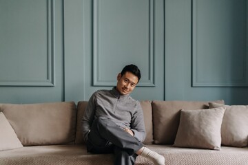 Asian man in fleece sitting in the living room in cold weather.