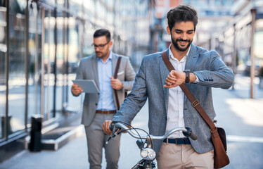 He never late. Smiling businessman looking at his watch on the way to office. Business, lifestyle concept