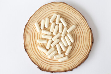 White enzyme supplements on a wooden round background