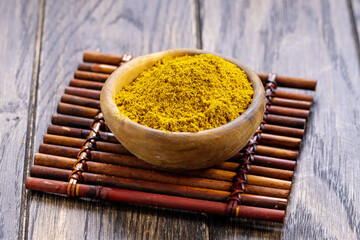 Curry powder is prepared mixture of spices in wooden bowl on table