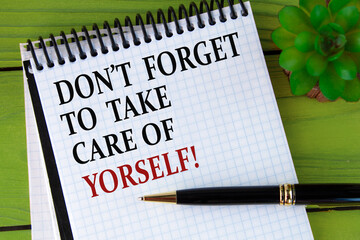 DON'T FORGET TO TAKE CARE OF YOURSELF! - words in a white notebook on a green wooden background...