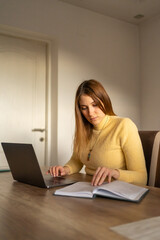 Fototapeta premium Young woman working from home and using her notebook. 