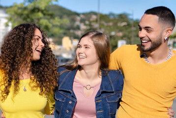 Happy millennial friends happily walk and hug on the city street - Young people having fun together - Youth and friendship concept.