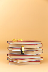 flash drive with yellow ribbon, on stack of red cover books