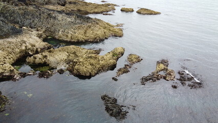 Rocky seashore, top view. Big rocks in the water. Seascape. Brown rock formation on body of water