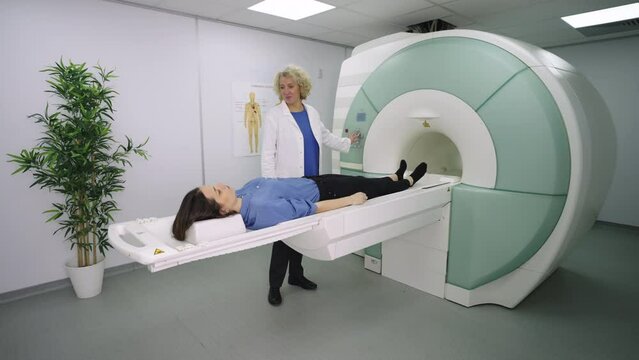 Medical technical assistant performing radiological scan of patient with magnetic resonance tomography MRI, modern technologies in medicine
