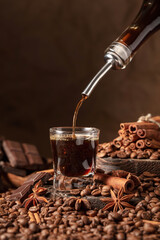 Coffee liquor is poured from a bottle into a glass.