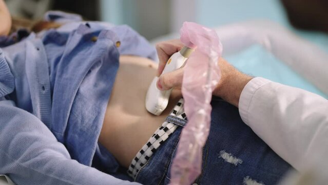 Little girl lying on examination bed at doctor appointment and having abdominal ultrasound scan. Close-up shot