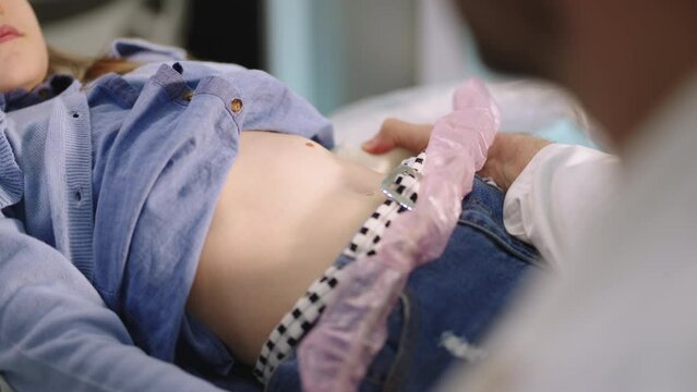 Medical examination of a smiling little girl by ultrasound equipment in the clinic