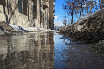Stream flowing along a city street, among drifts of snow blackened by mud. Spring. Selective focus