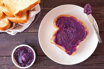 Toast with ube halaya jam. Sweet, trendy, purple yam spread. Top view table scene on a dark wood...