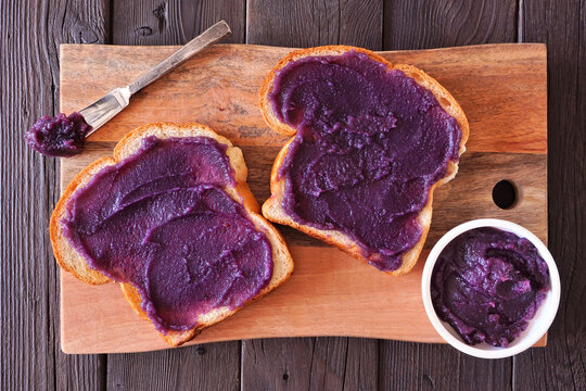 Toast with ube halaya jam. Sweet, trendy, purple yam spread. Above view on a wood serving platter.