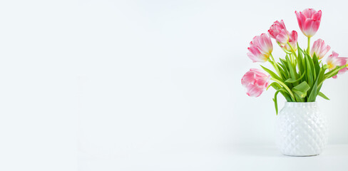 tulips in a white vase on a white background. Banner. Space for text on the right