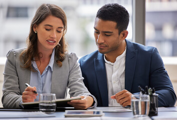 Getting a coworkers opinion. Shot of two young businesspeople sitting together in the office and having a discussion while using a digital tablet.