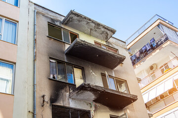Apartment building after a fire, sooty windows and balconies from black smoke. Abandoned house,...