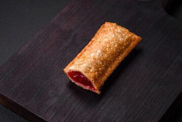 Delicious fresh crispy pie with cherry jam on a wooden cutting board