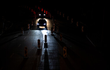 Cars on a road with roadworks. Works on the road. Night traffic. - obrazy, fototapety, plakaty