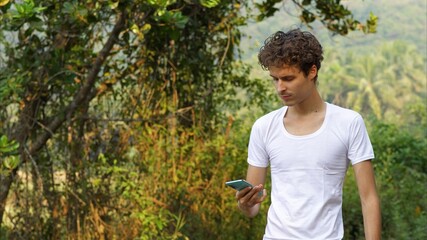 man with phone in hands on the background of tropical trees