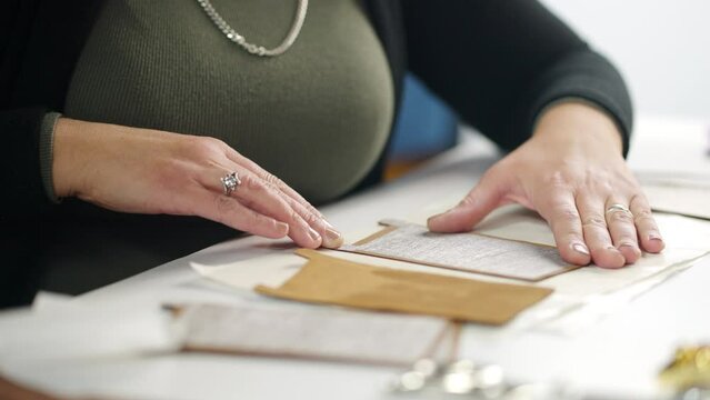 Seamstress attaching leather parts with glue for bags production on a work table in slow-motion. Close-up workshop of a skinner during process sticking items of a leather accessories