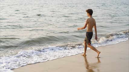 Man walks to the sea on a sandy beach