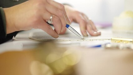 Female tailor is using adhesive for compounding parts of leather cover. He is smearing edge using brush on a table in slow-motion, preparing to assembly of the items