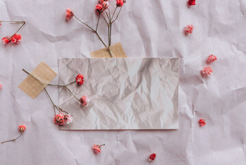 Mock up of blank white card on crumpled background with dry flowers.