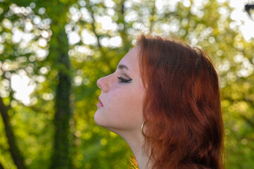 Portrait of a young pretty redhead girl in profile, head slightly up