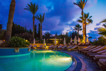 Fototapeta na wymiar Garden and pool in 5 star hotel of Greek islands or Cyprus island and amazing skyscape in blue time