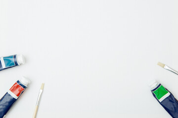 Multi-colored tubes with oil or acrylic paint and brushes on a white background. copy space