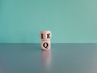 IQ or EQ symbol. Turned cube, changes words IQ, intelligence quotient to EQ, emotional quotient. Beautiful blue background. Concept of emotional and intelligence quotient. Copy space.