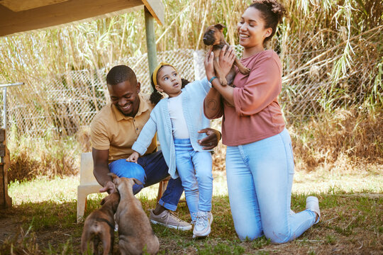 Family, dog adoption and pet outdoor with a happy mother, girl and dad with a puppy. Happiness, love and animal shelter care of a mom, child and man hug and hold dogs together with a smile in a park