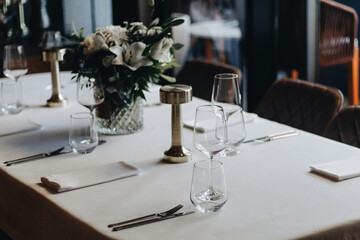tableware Glasses, flower fork, knife served for dinner in restaurant with cozy interior