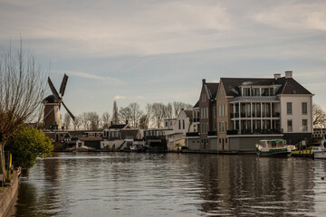 typical dutch scene with windmill above water next to boats and houses in city of Bodegraven in Netherlands holland