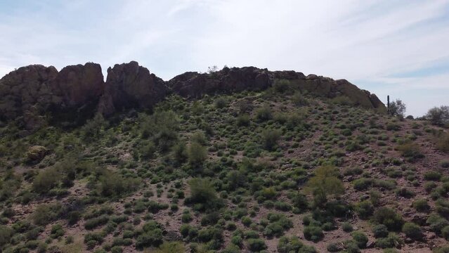 Aerial pan across rocky desert hill reveals residential housing beyond 
